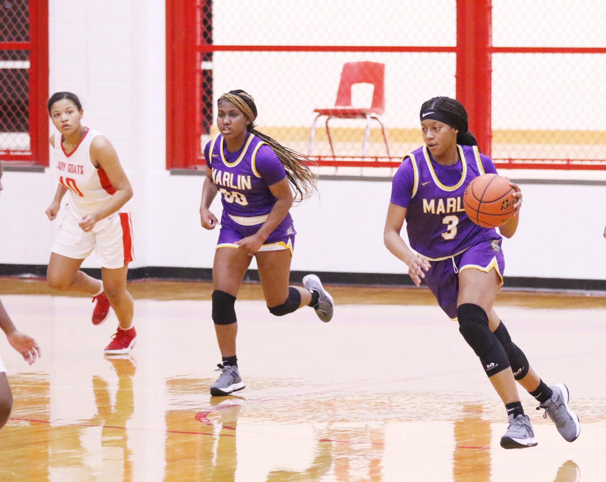 Marlin's Taliyah Davis dribbles toward the basket ahead of a Groesbeck player as teammate Kendria Mason (10) runs with her during a game in Groesbeck on Friday night.Photo by Angela Crane/For the Marlin Democrat